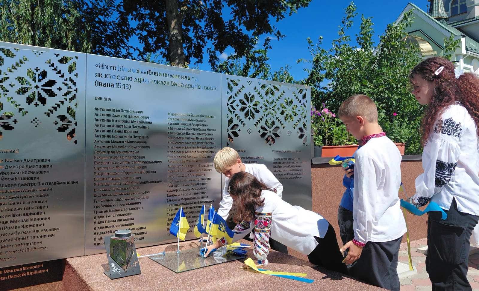 Діти встановлюють синьо-жовті прапорці біля меморіалу полеглих Захисників