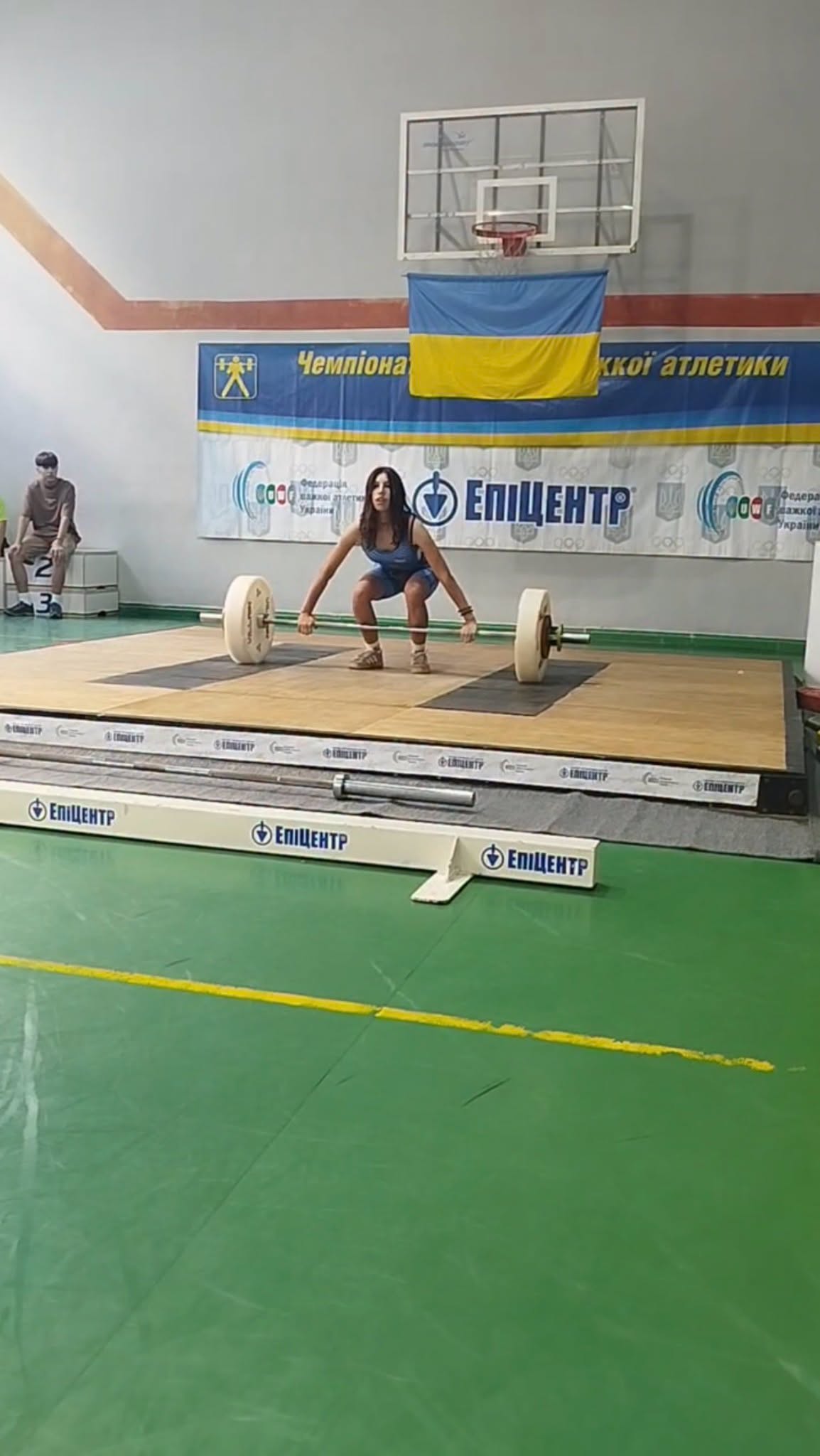 Юна спортсменка виконує вправу зі штангою на помості