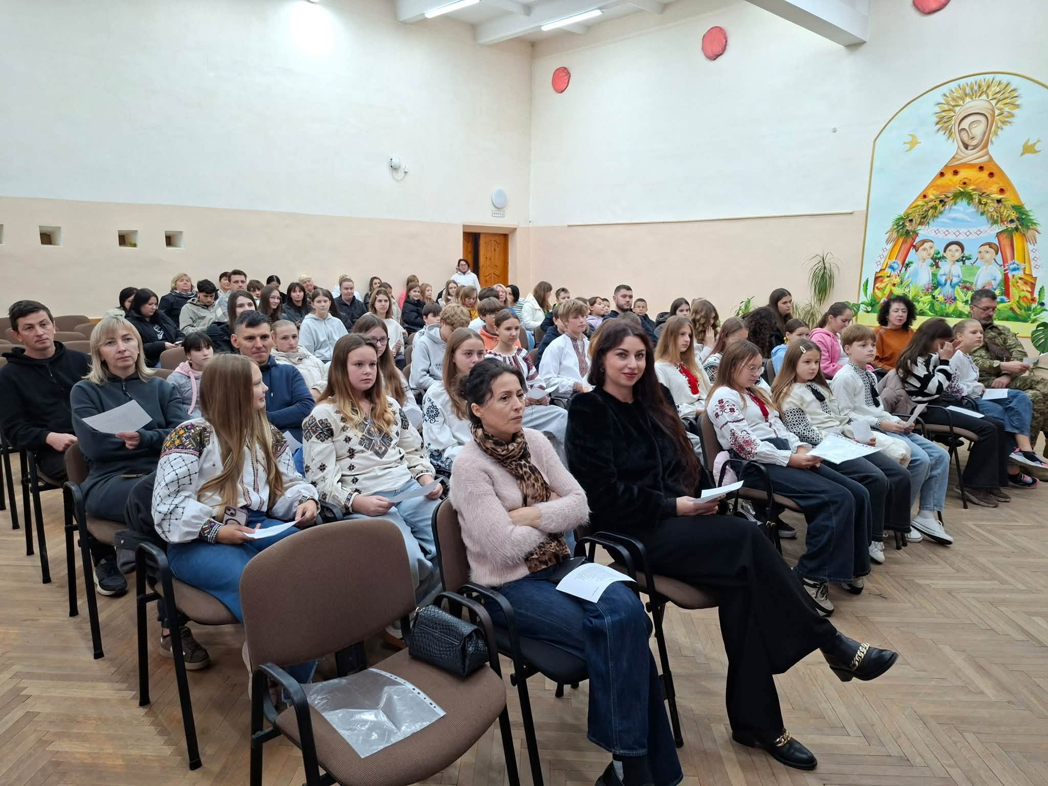 Учасники заходу сидять тримаючи аркуші з текстами