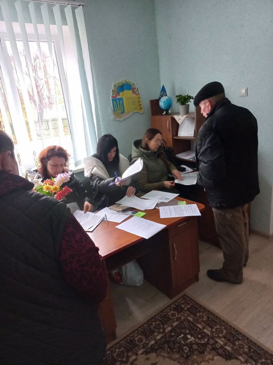 Жінки за столом переглядають документи відвідувача
