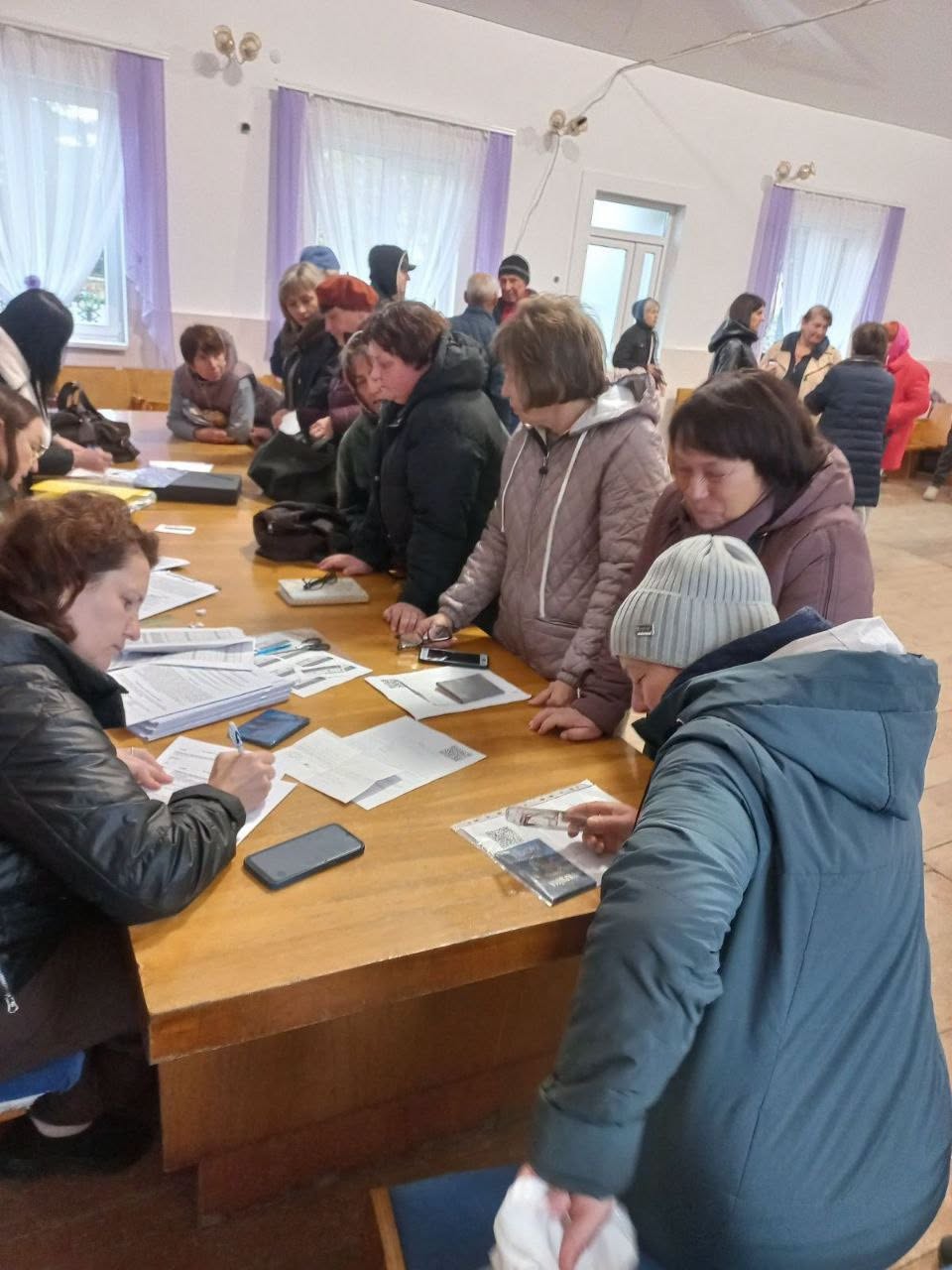 Люди з документами зібралися біля столу заповнення бланків.
